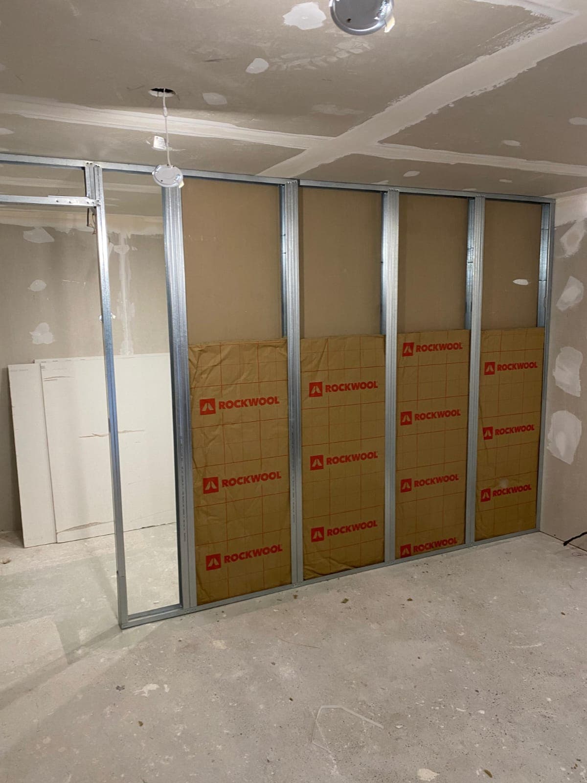 Mur à ossature métallique avec panneaux isolants Rockwool posés dans une pièce en construction.